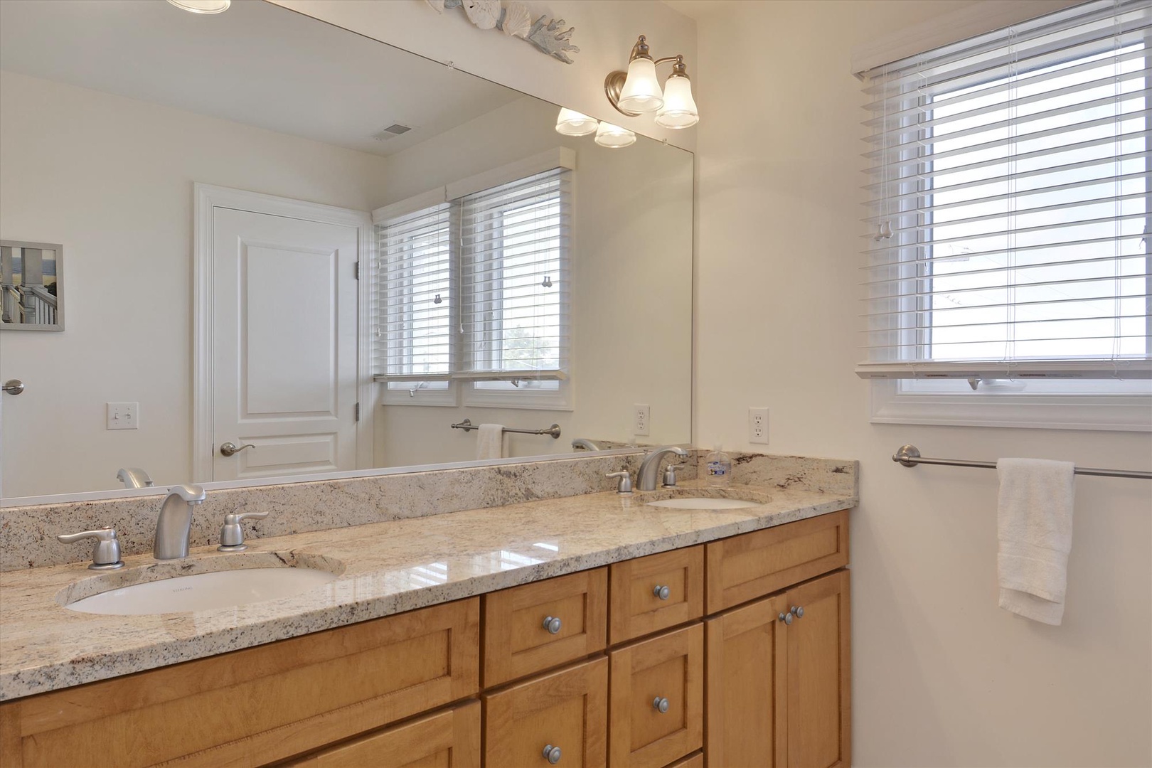 Freshen up in your spacious dual-sink bathroom with granite counters, warm wood cabinetry, and plenty of natural light streaming through the windows.
