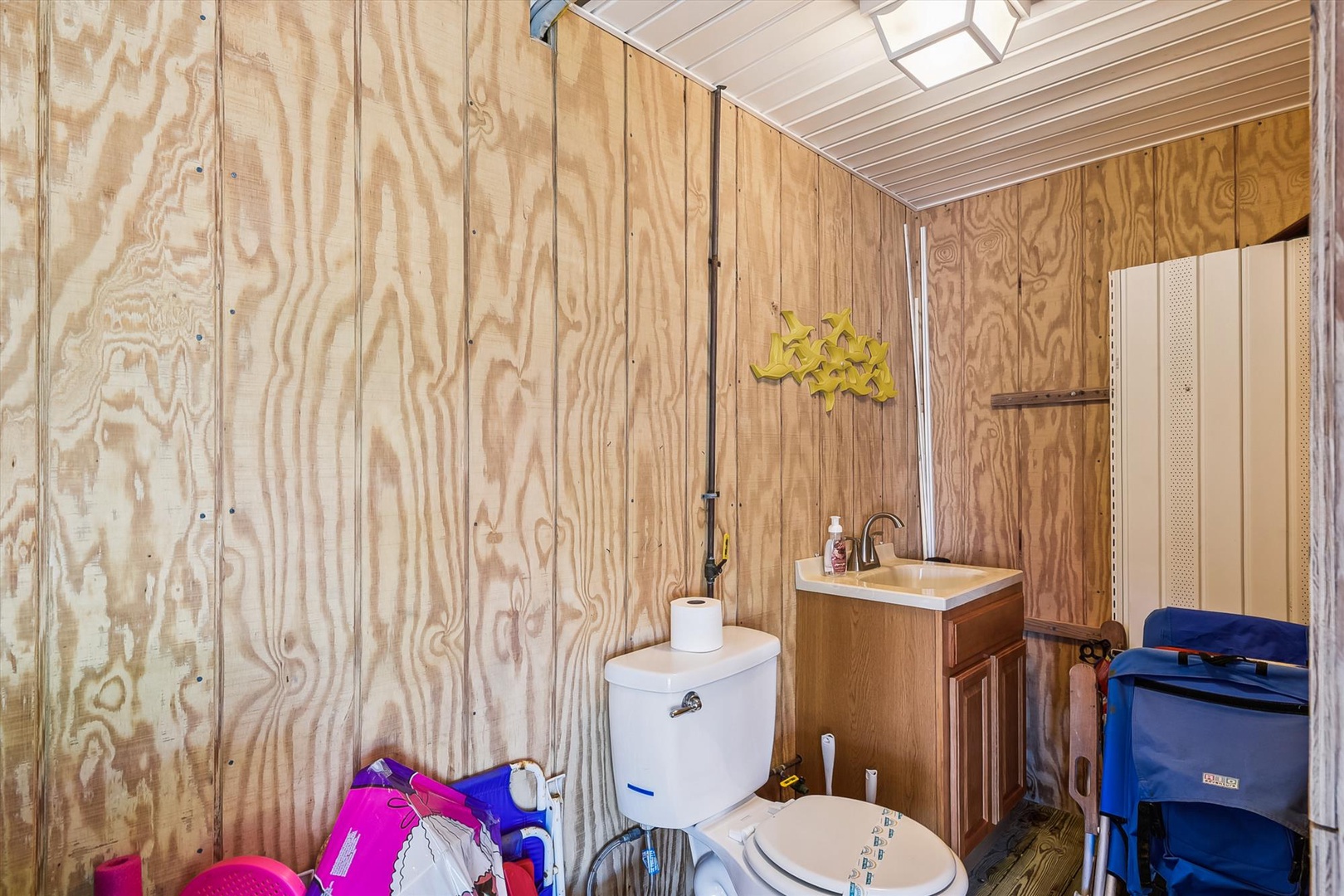 Your private bathroom features plywood paneling for rustic charm, a skylight for natural light, and includes a toilet, vanity sink, and storage—all the essentials for your stay.