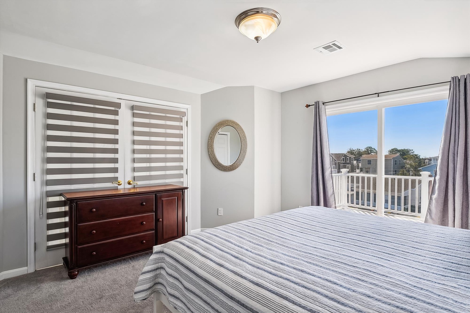 Wake up to brilliant blue skies and coastal breezes in this serene bedroom, where your private balcony frames views of the water and surrounding homes.