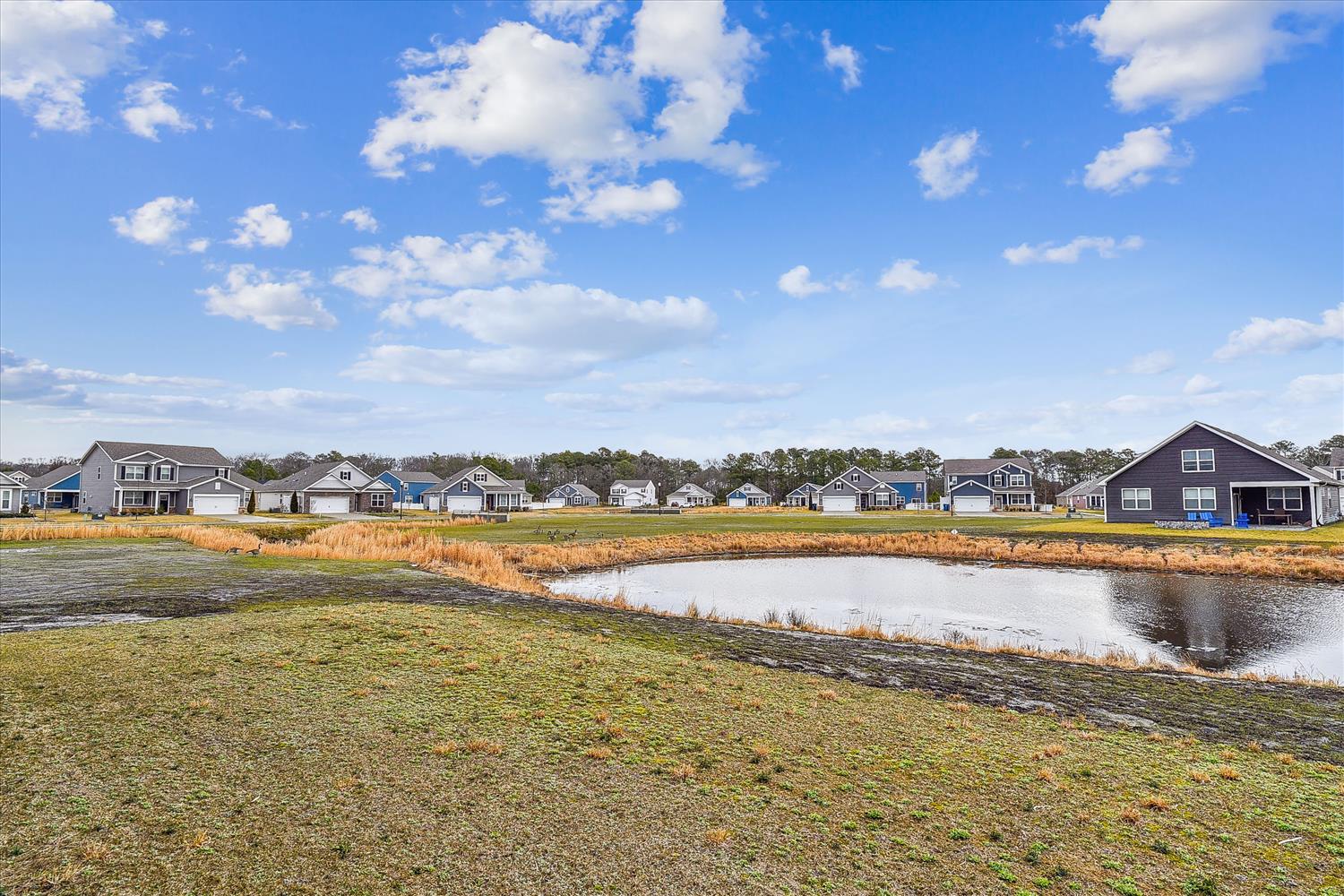 Peaceful neighborhood setting features a serene pond and spacious green lawns, creating a relaxing backdrop for this property located in a quiet residential community.