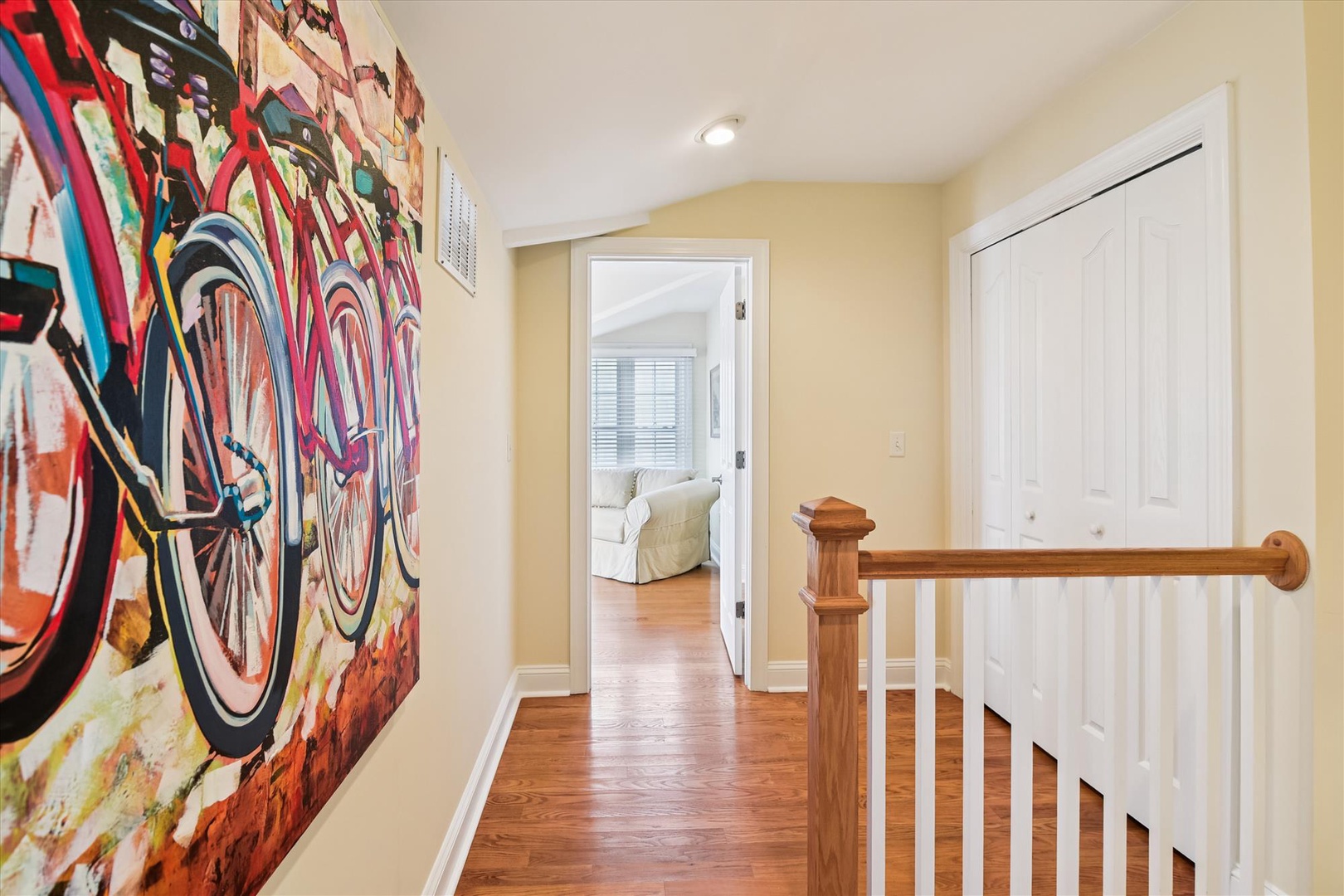 Vibrant bicycle artwork adds personality as you move upstairs, with warm wood finishes and inviting glimpses of cozy spaces ahead.