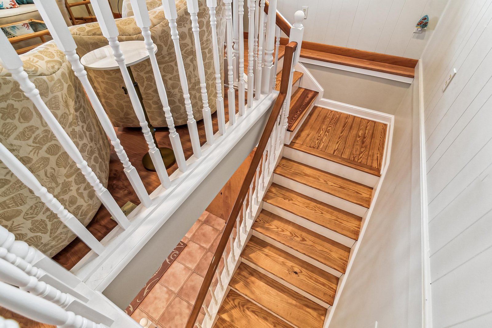 A warm hardwood staircase with classic white railings connects the levels of your home, offering easy access and coastal charm.