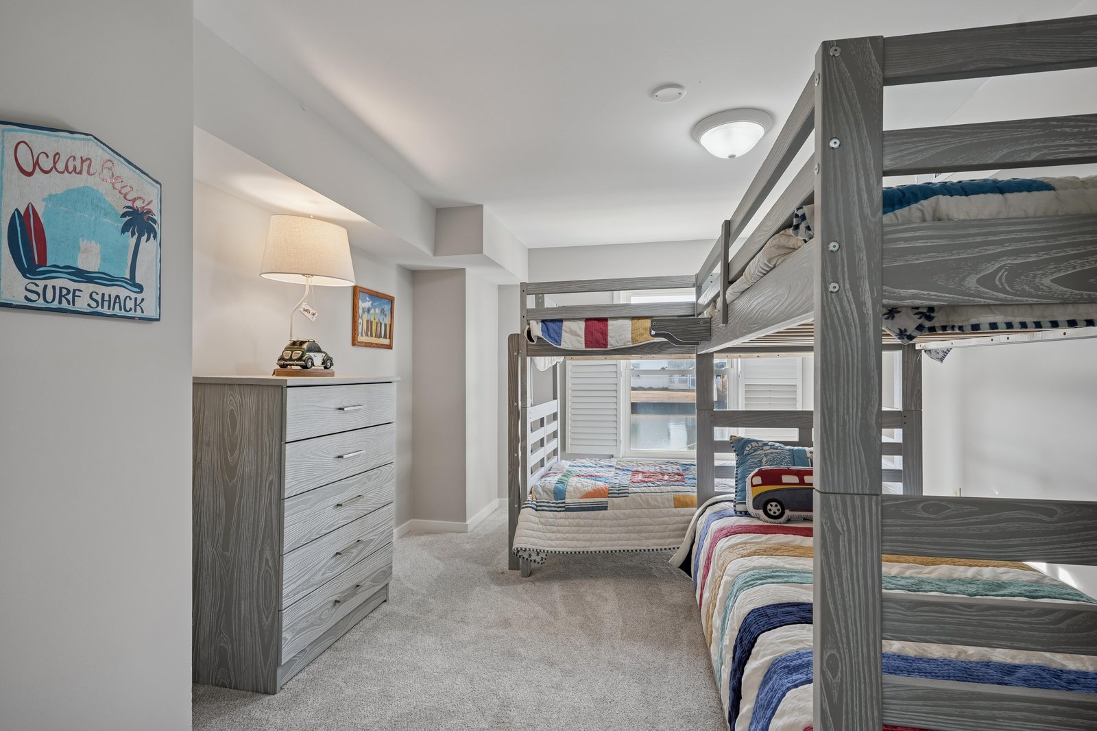 Charming bunk room with coastal flair awaits your crew, featuring sturdy twin beds, playful surf shack décor, and plenty of storage for everyone's belongings.