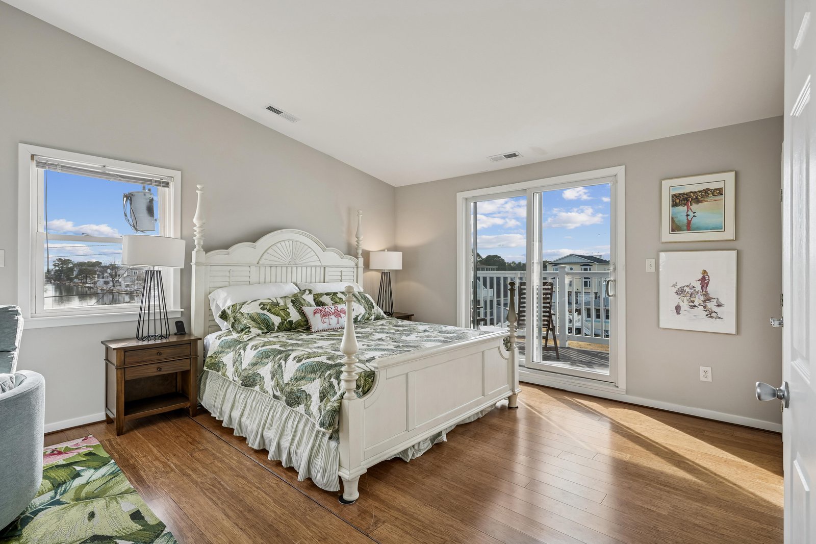 Step into your serene coastal retreat with a plush four-poster bed dressed in tropical linens, warm hardwood floors underfoot, and French doors opening to a private balcony where waterfront breezes invite you to unwind.