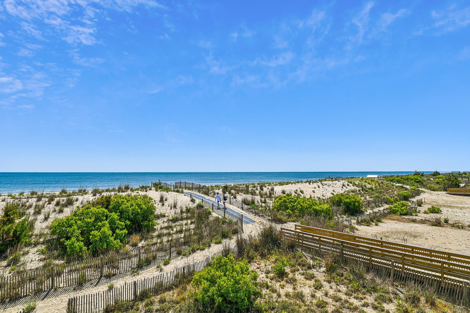 Pristine beach access with boardwalk leading through natural dunes to crystal-clear turquoise waters. This coastal setting offers an idyllic escape for seaside relaxation.