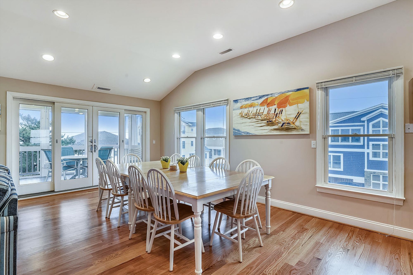 Gather around this inviting dining table, where coastal breezes flow through open French doors and sunlight fills the space. Picture yourself sharing meals with loved ones, enjoying fresh flavors and laughter in this bright, welcoming retreat.