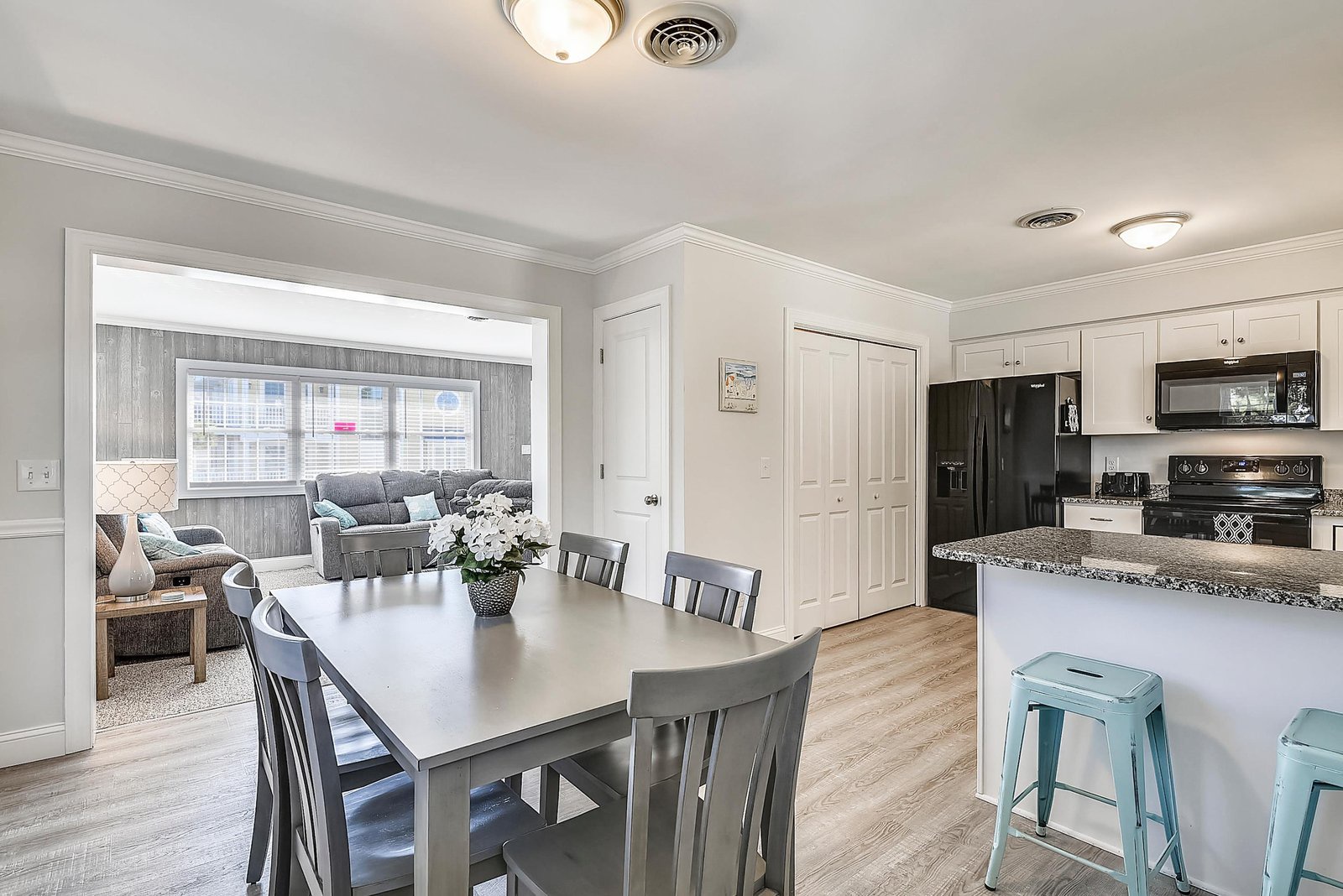 Step into your bright, open living space where modern kitchen meets cozy dining. Fresh flowers, soft seating, and a seamless flow invite you to relax and feel right at home.