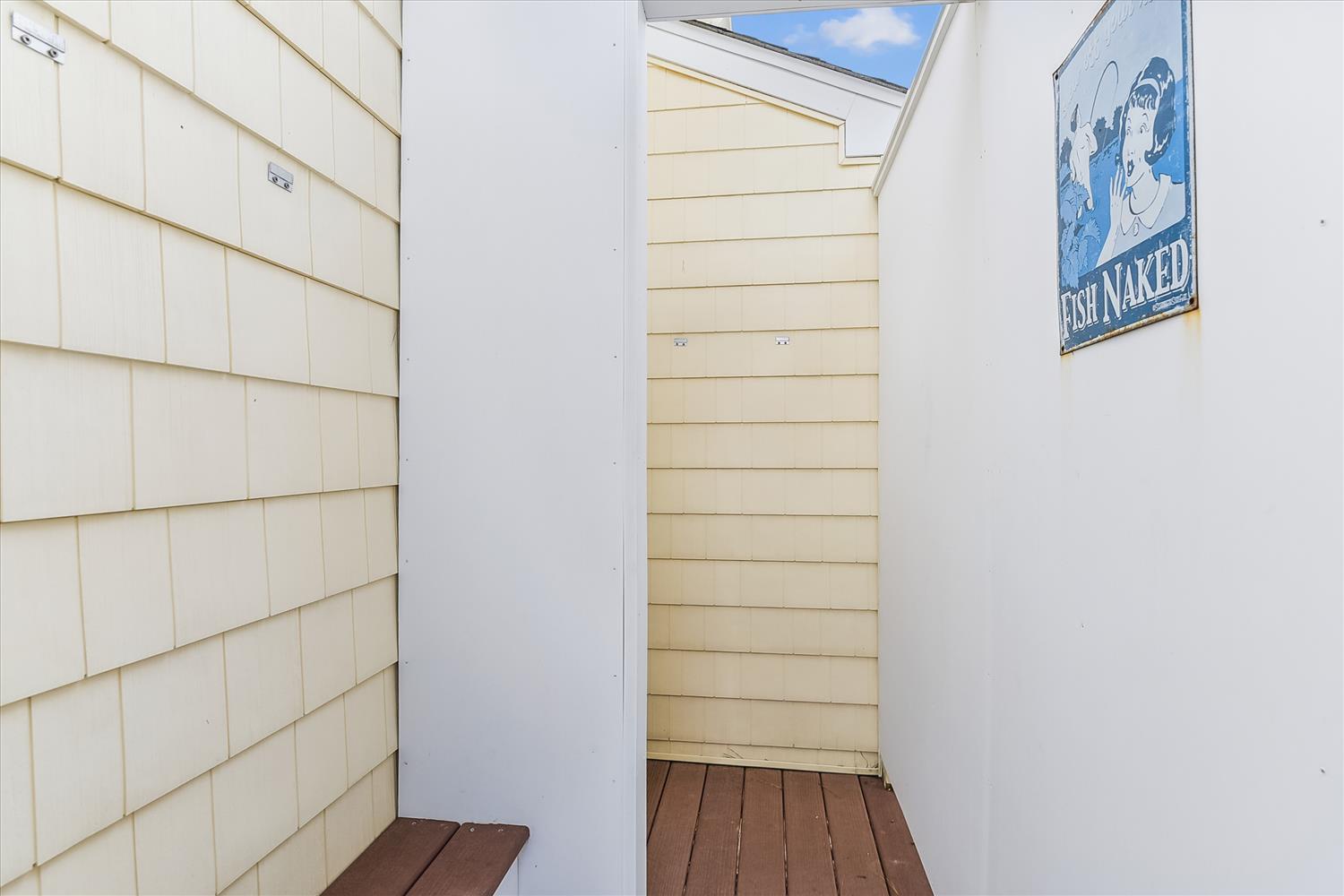 A narrow private outdoor shower area with coastal charm—rinse off after the beach under the open sky.