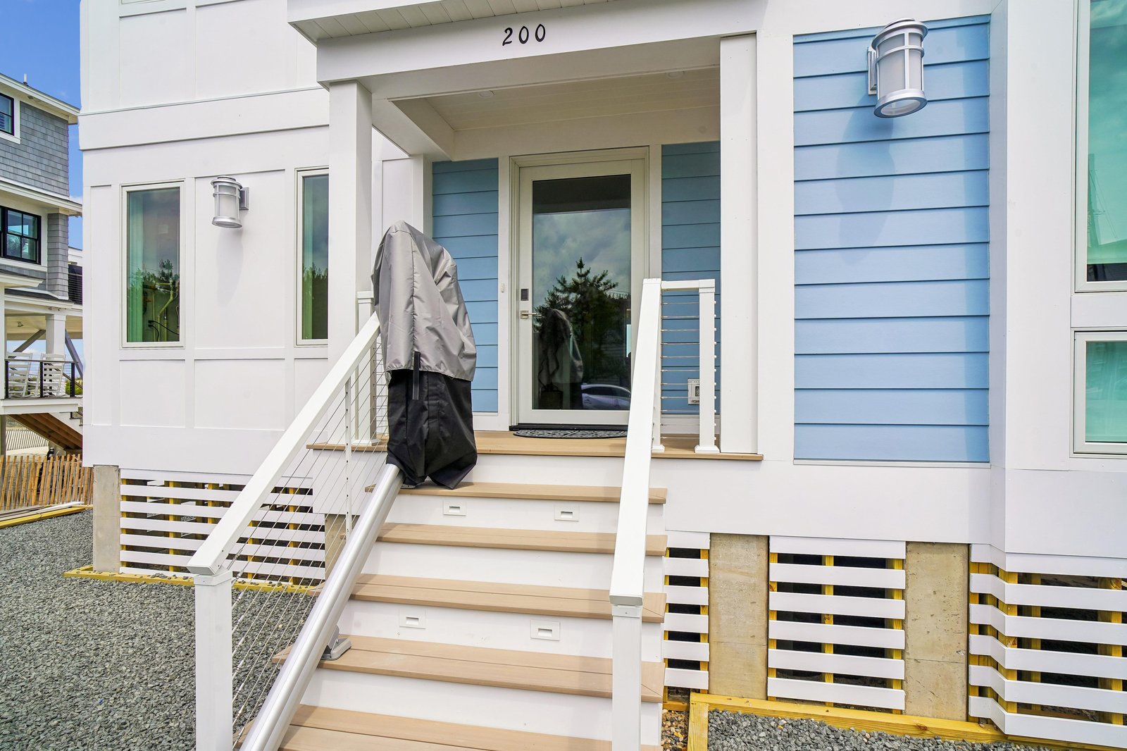 Welcome to your coastal retreat—a beach house nestled in a quiet seaside neighborhood, marked by charming blue siding and the inviting entrance at 200.