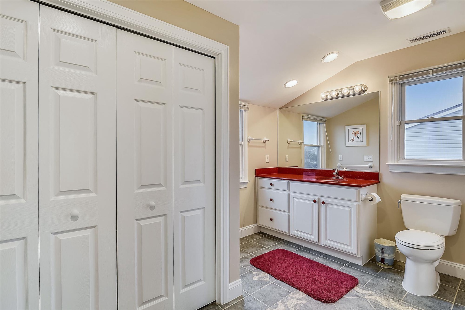 Step into your bright, spacious bathroom featuring a striking red countertop, dual sinks, ample storage, and modern fixtures—everything you need to feel refreshed and at home.