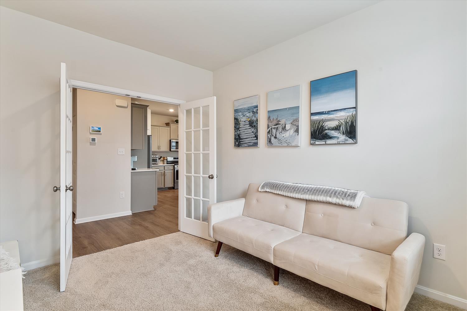 Sink into your comfortable sofa while coastal artwork sets a serene mood. French doors reveal the bright kitchen, creating an open, airy feel.