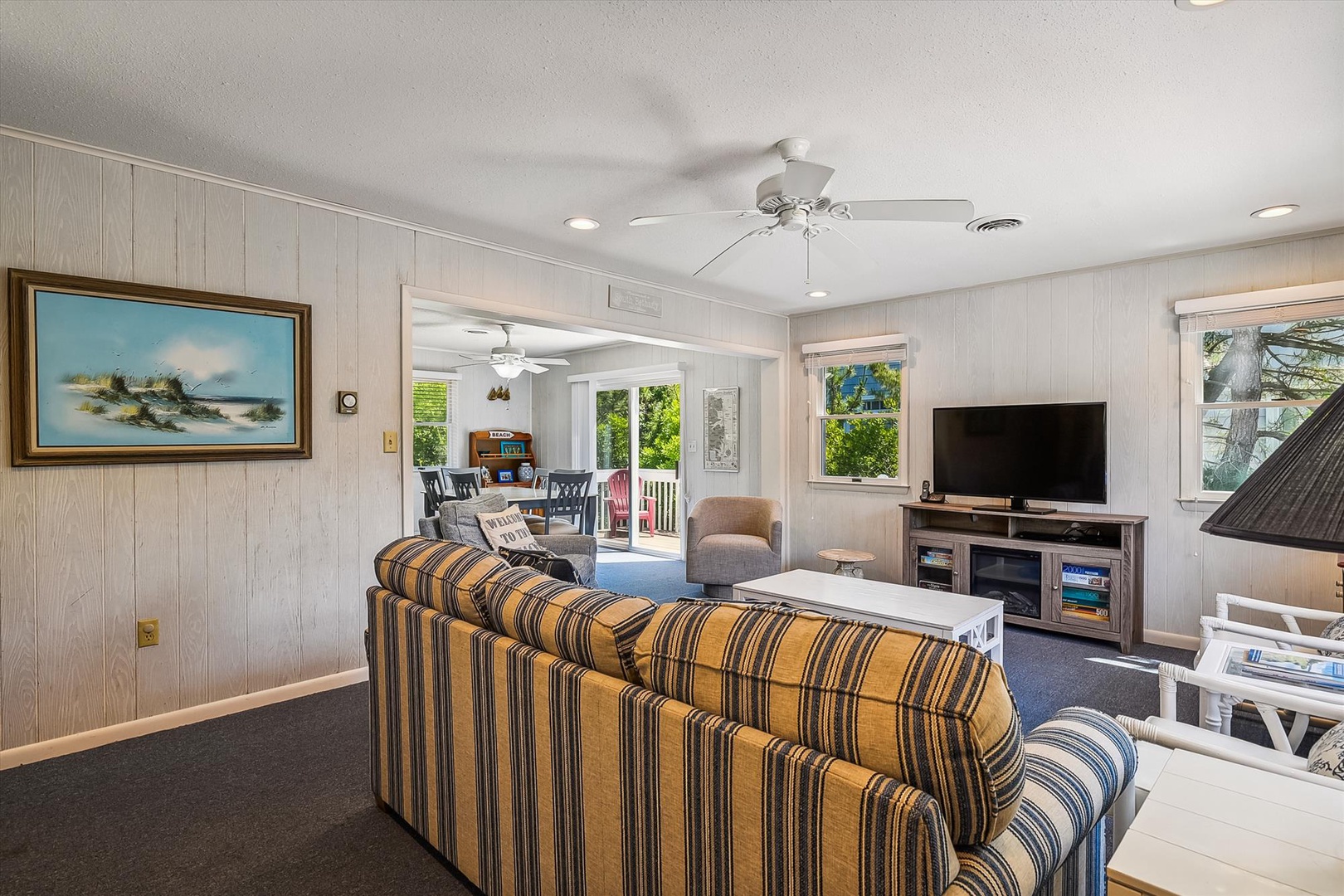 You'll love gathering in this bright, airy living room where coastal charm meets comfort. Relax on plush sofas, enjoy your favorite shows, and step out to sunshine-filled spaces just beyond.