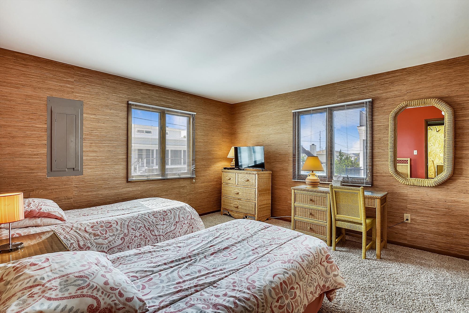 Relax in a warmly-lit bedroom with rich wood-paneled walls, cozy beds dressed in soft linens, charming vintage furniture, and natural light streaming through your windows.