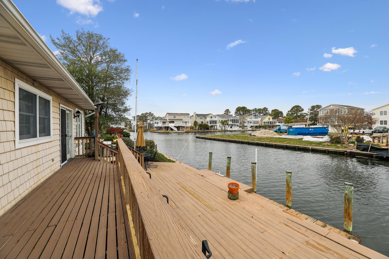 A waterfront property along a peaceful residential canal with private dock access and surrounding coastal homes visible across the water.