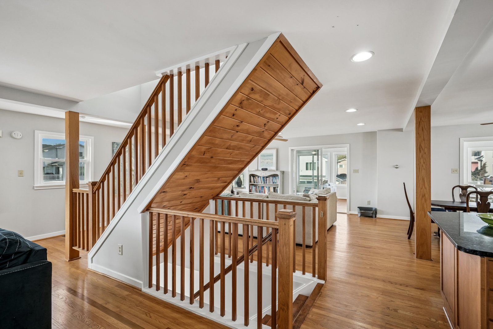 Bright, open living space with polished wood floors and a striking wooden staircase inviting you to explore the upper level at your leisure.