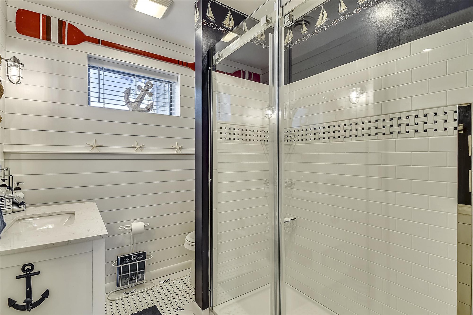 Step into your charming nautical-themed bathroom with crisp white shiplap, maritime accents, and a sparkling walk-in shower that makes every morning feel like a seaside escape.