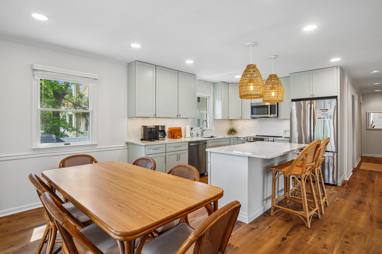 Your fully equipped kitchen and dining area blend modern amenities with coastal-inspired charm, perfect for preparing memorable meals together under warm woven pendant lights.