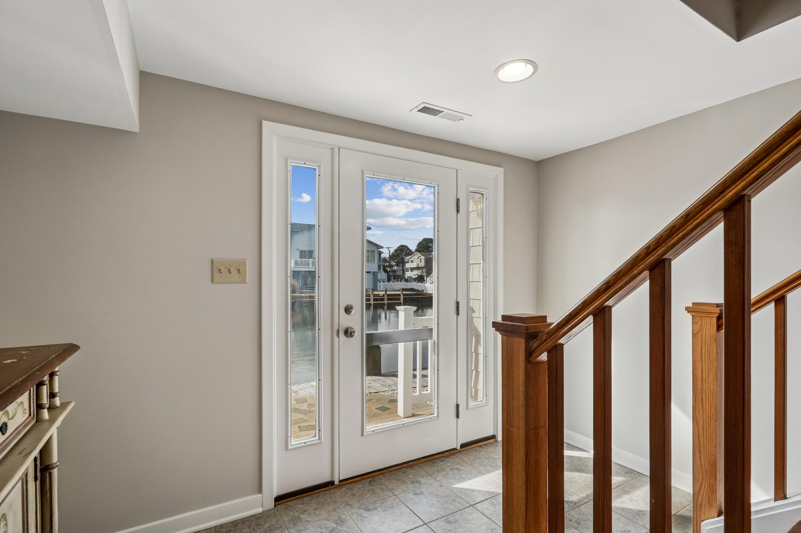 Through these doors, your waterfront escape awaits—step straight onto a private deck overlooking calm waters and neighboring homes nestled along the shore.
