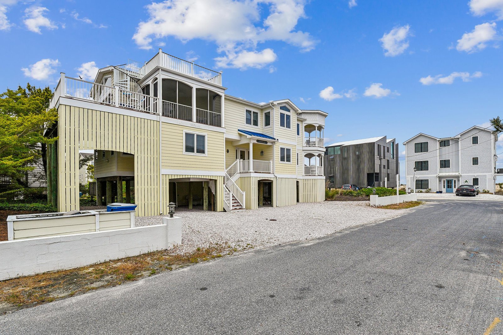 A spacious coastal home with multiple levels, screened porches, and deck areas, located in a quiet beach neighborhood just moments from the shore.