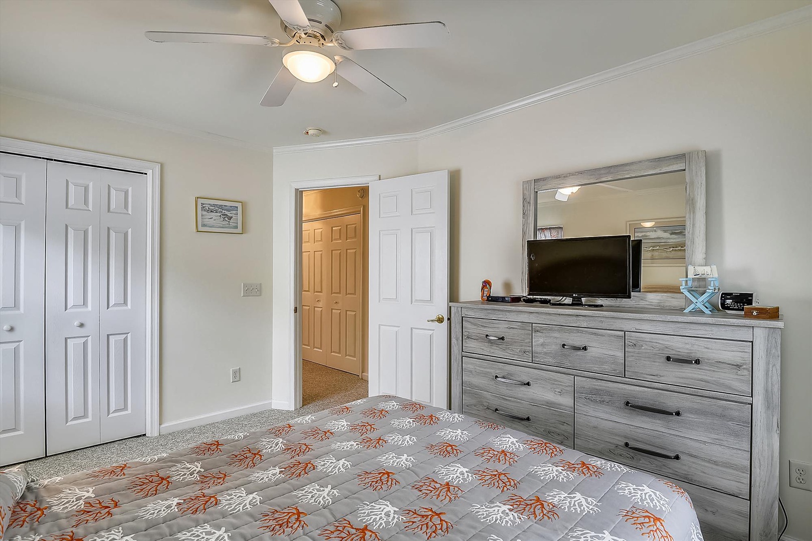 Your peaceful bedroom retreat features a plush bed, modern entertainment setup, and ample storage. Drift off under the gentle ceiling fan as soft lighting creates the perfect atmosphere for rest.