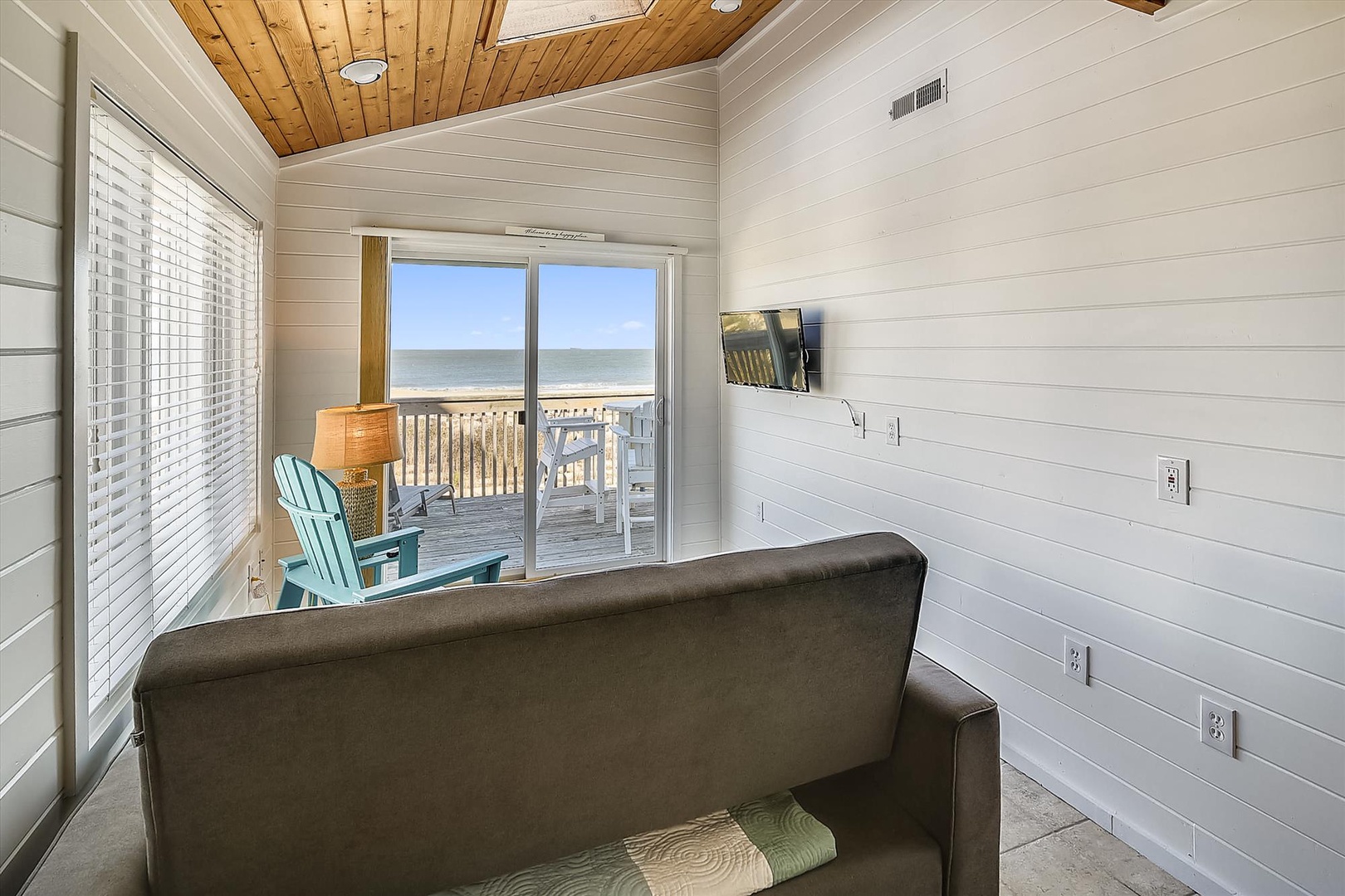 Relax in your cozy living space with beautiful shiplap walls and warm wood ceilings, with direct access to your private deck overlooking the beach and ocean waves.