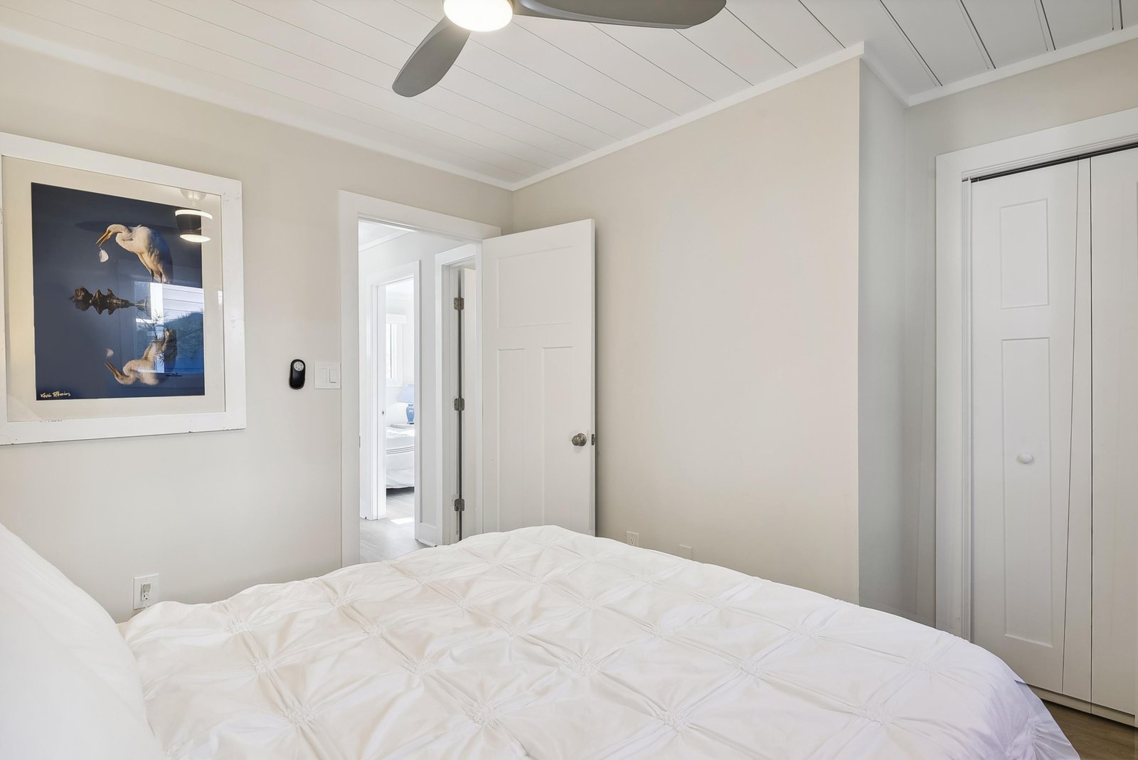 Rest easy beneath vaulted shiplap ceilings and a gentle ceiling fan, your serene bedroom retreat with crisp linens and soft neutral tones.