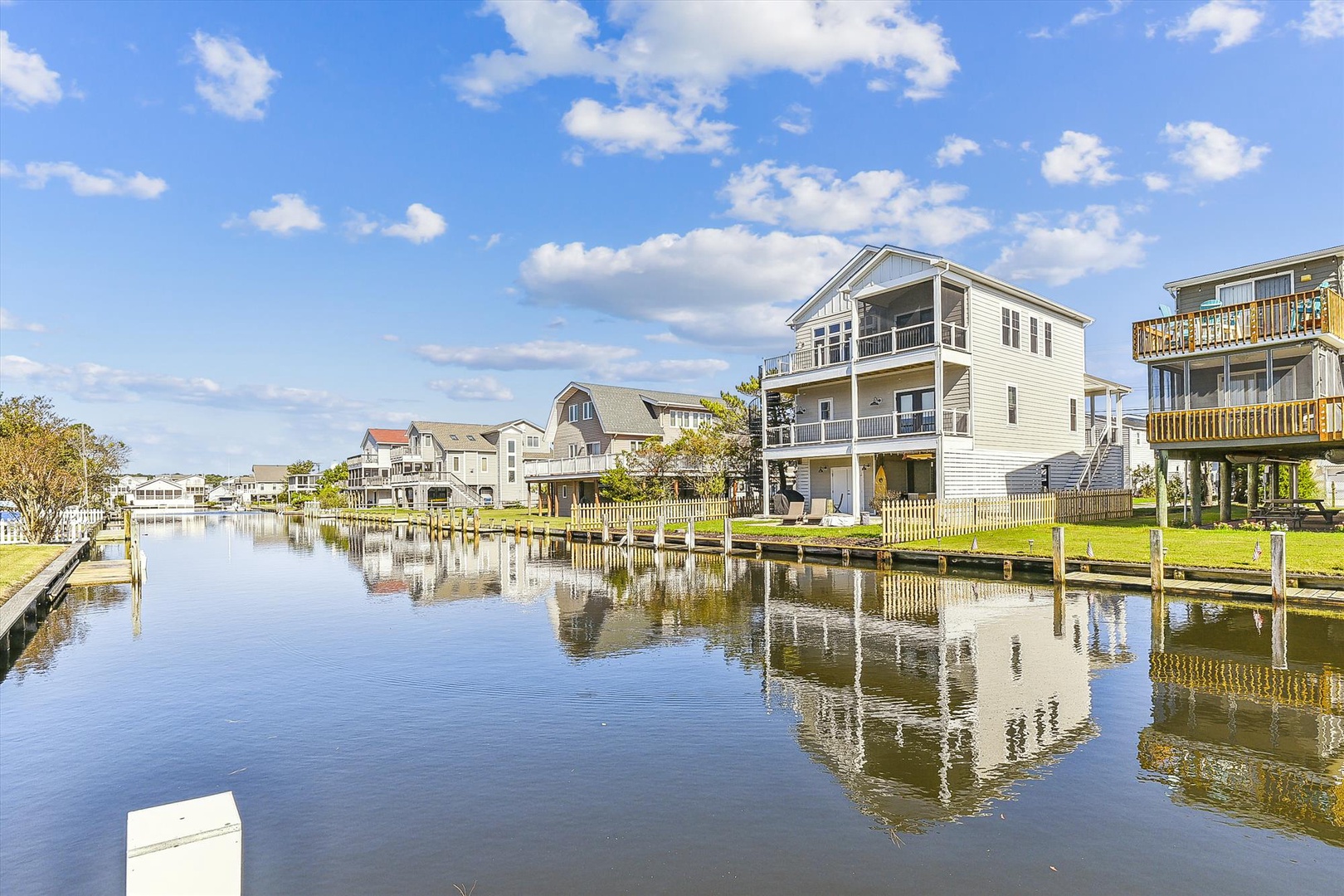 Coastal canal community featuring elevated vacation homes, private docks, and peaceful waterways perfect for boating enthusiasts. This property sits in a serene neighborhood setting under sunny skies.