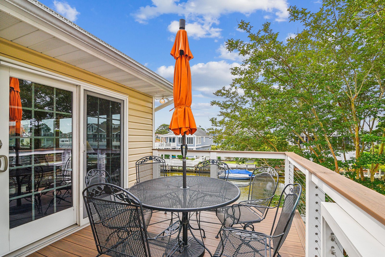 Step out onto your private deck where mornings begin with coffee and waterfront breezes. The table seats six comfortably, perfect for leisurely meals under the shade of a vibrant umbrella as you take in peaceful water views.