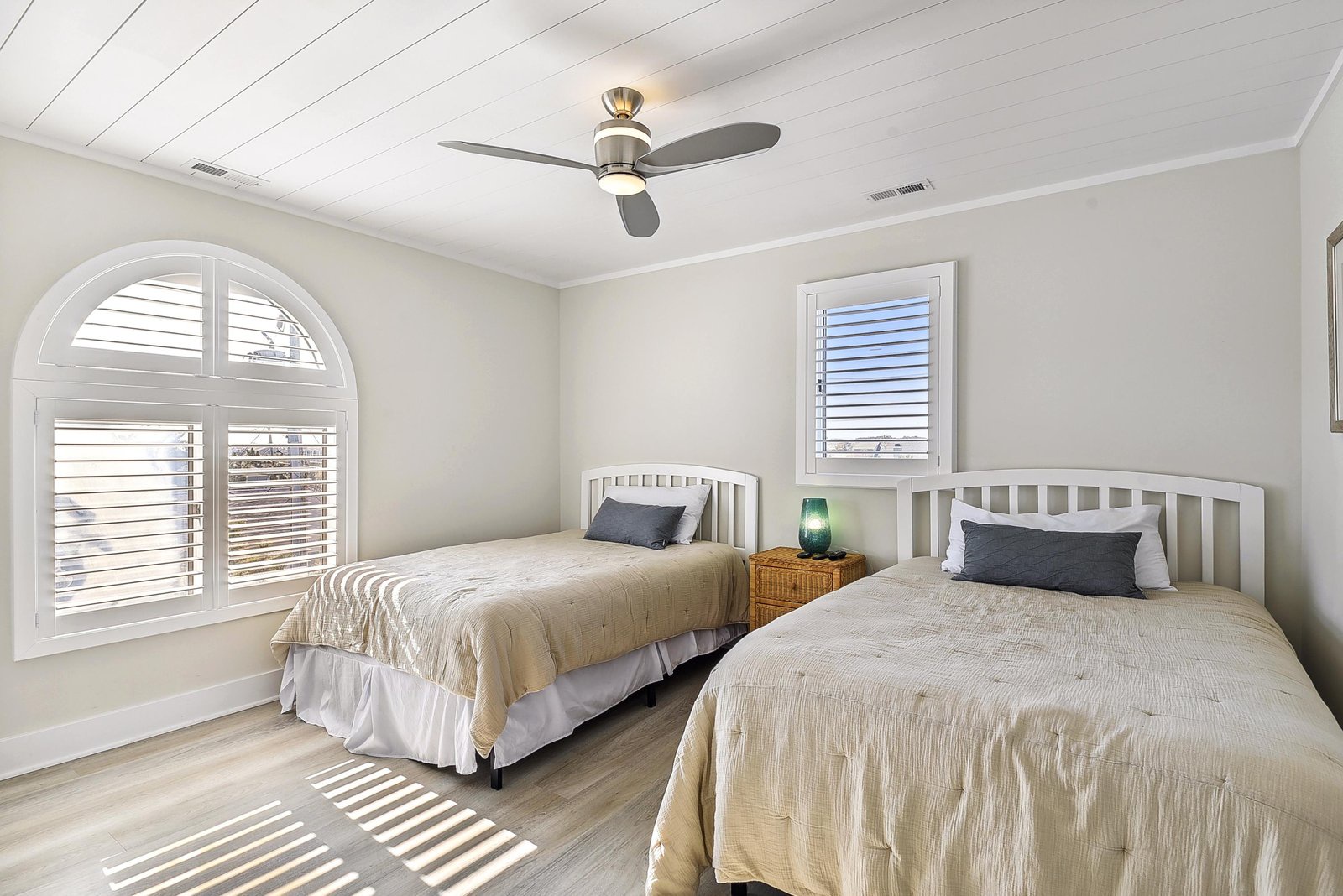 Sink into crisp linens and coastal calm in your bright twin bedroom, where arched windows and soft natural light create the perfect retreat after your beach adventures.