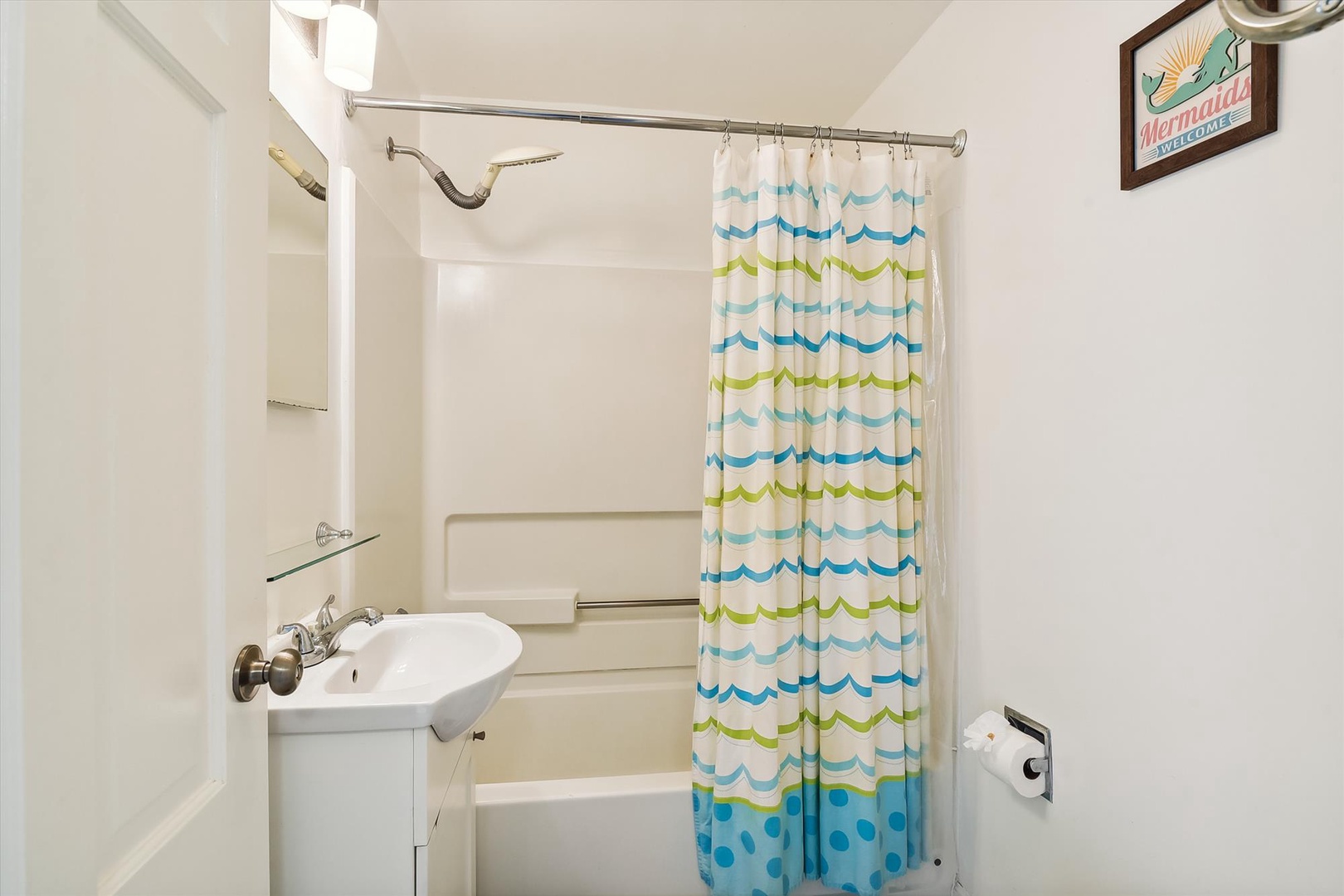 A cheerful bathroom awaits with a playful mermaid theme and clean, bright fixtures. Step into the shower after a fun day, dry off with fresh towels, and enjoy the whimsical coastal touches.