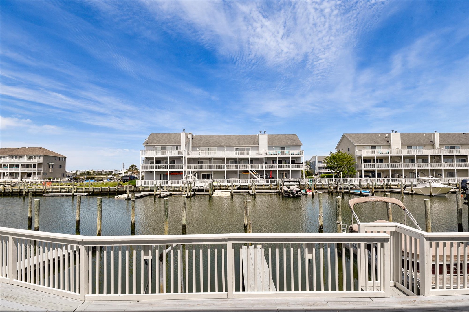 A multi-story waterfront property complex overlooks a marina with boat slips and docks. The building features stacked balconies and is part of a developed waterfront neighborhood.