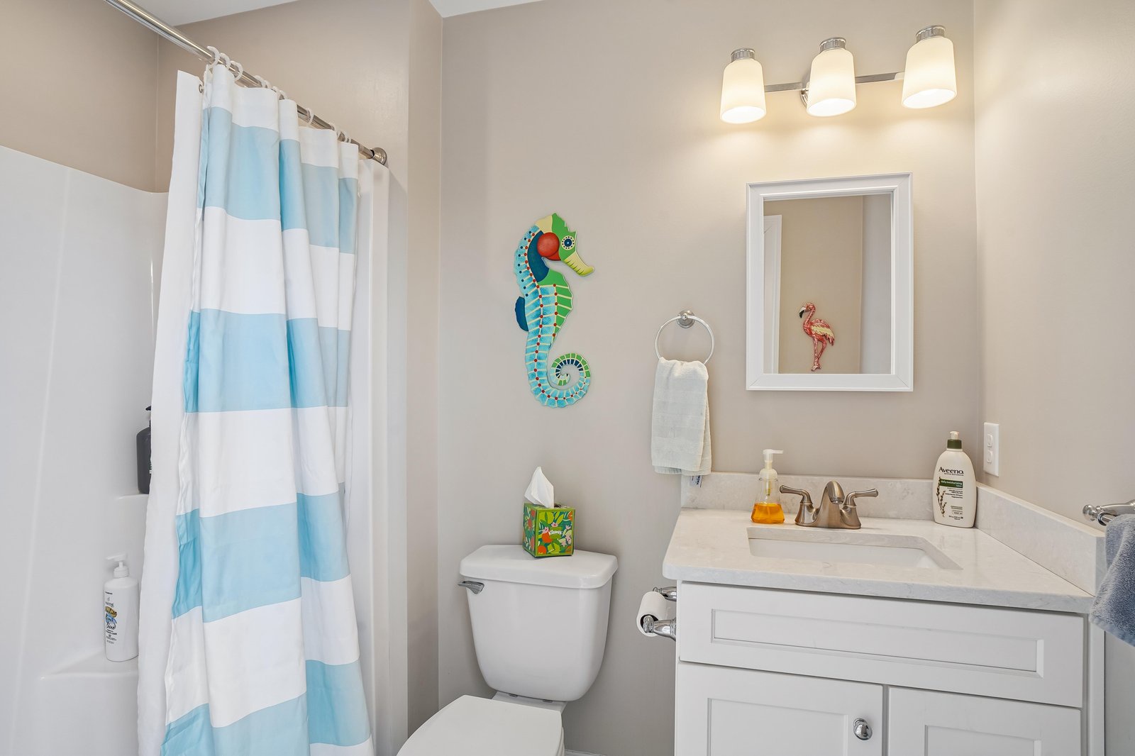 Step into your freshly updated bathroom, complete with cheerful coastal decor and soft lighting. The vanity, shower, and thoughtful touches make morning routines feel like a breeze.