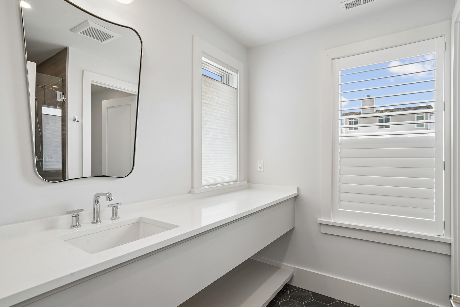 Freshen up in this sleek, sunlit bathroom with a spacious vanity and crisp white finishes that help you start your day feeling relaxed and ready.