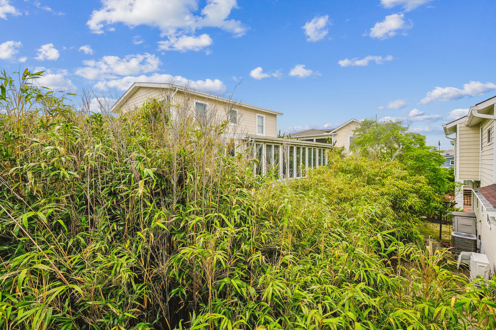 A two-story property nestled in a quiet residential neighborhood, surrounded by natural greenery and neighboring homes under a clear blue sky.