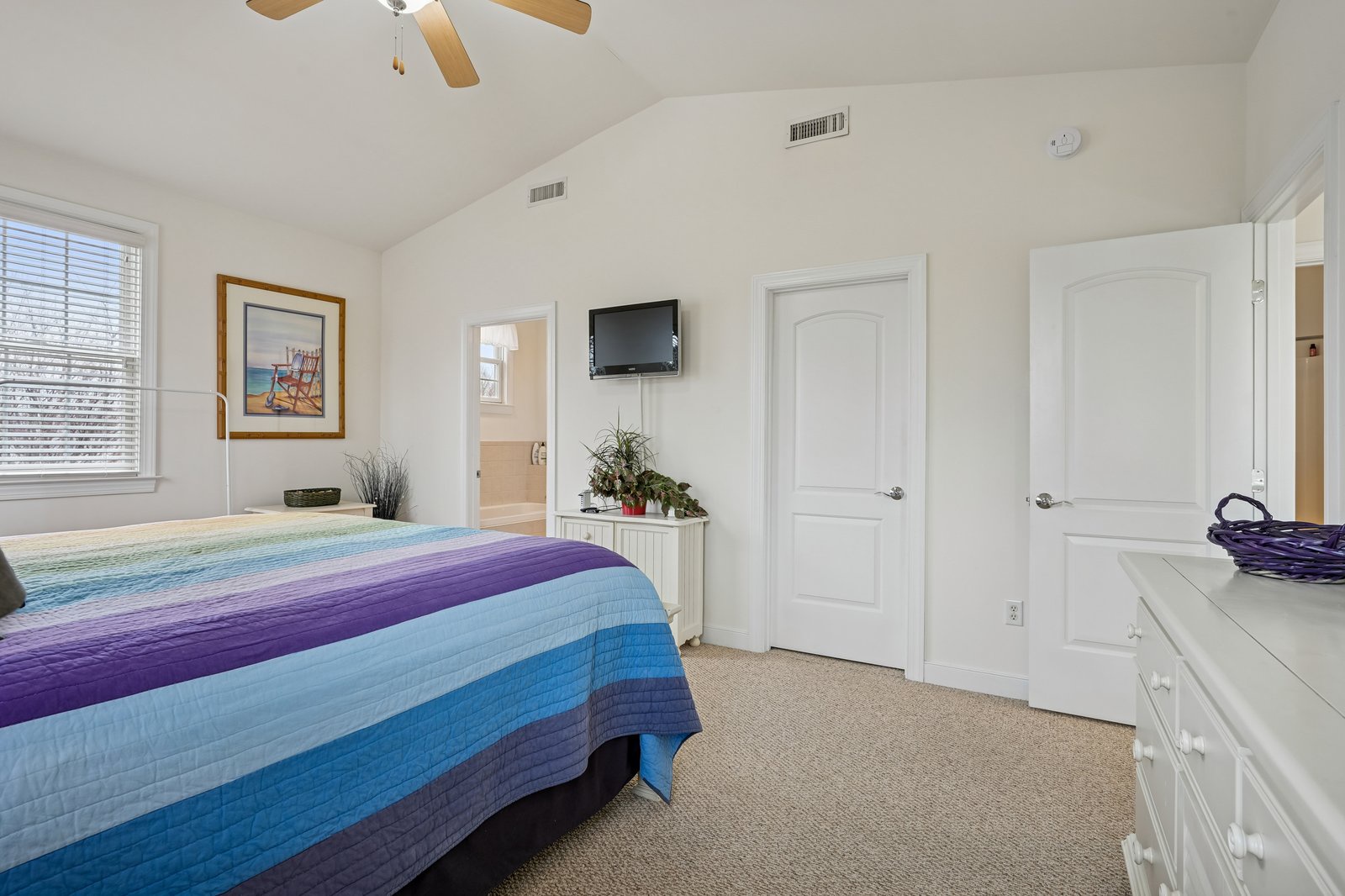 Unwind in your bright bedroom with colorful bedding, ceiling fan, and TV for cozy evenings.