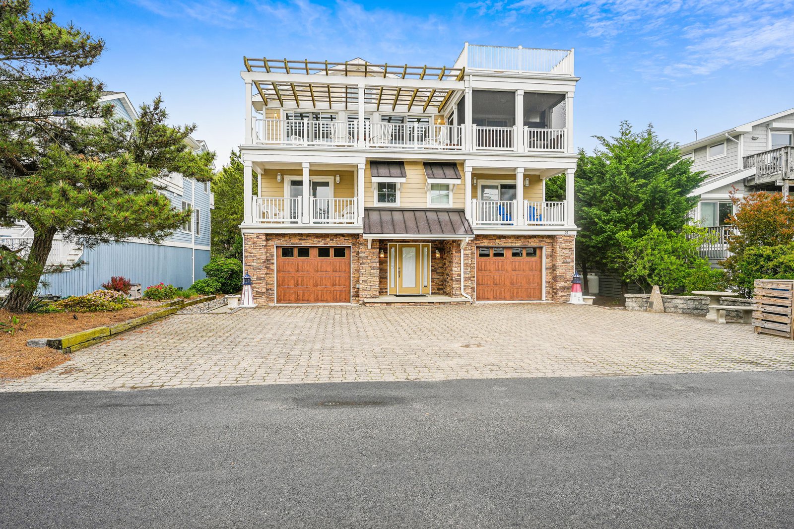A striking three-story beach home featuring inviting wrap-around decks, spacious double garages, and charming coastal architecture set within a beautifully landscaped neighborhood.