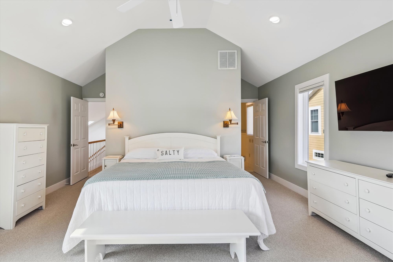 Unwind in your serene coastal retreat with vaulted ceilings, plush bedding, and soft lighting that create a peaceful escape for your perfect night's rest.