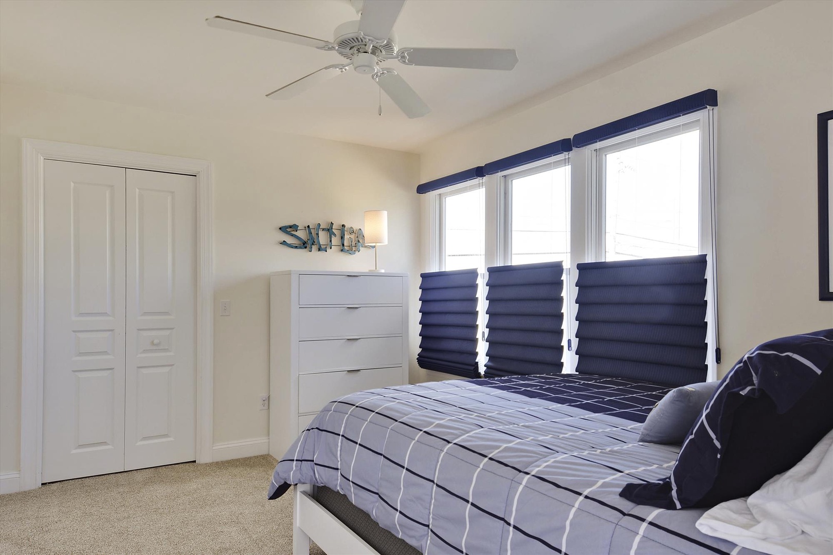 Your peaceful bedroom retreat features a comfortable bed, ceiling fan for cool nights, and blue accents that create a calming coastal vibe.