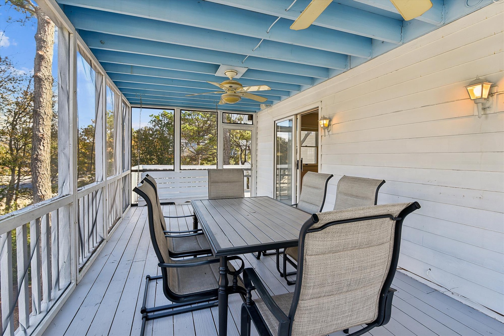 Your covered porch offers breezy dining with ceiling fans overhead and peaceful tree views through screened walls.