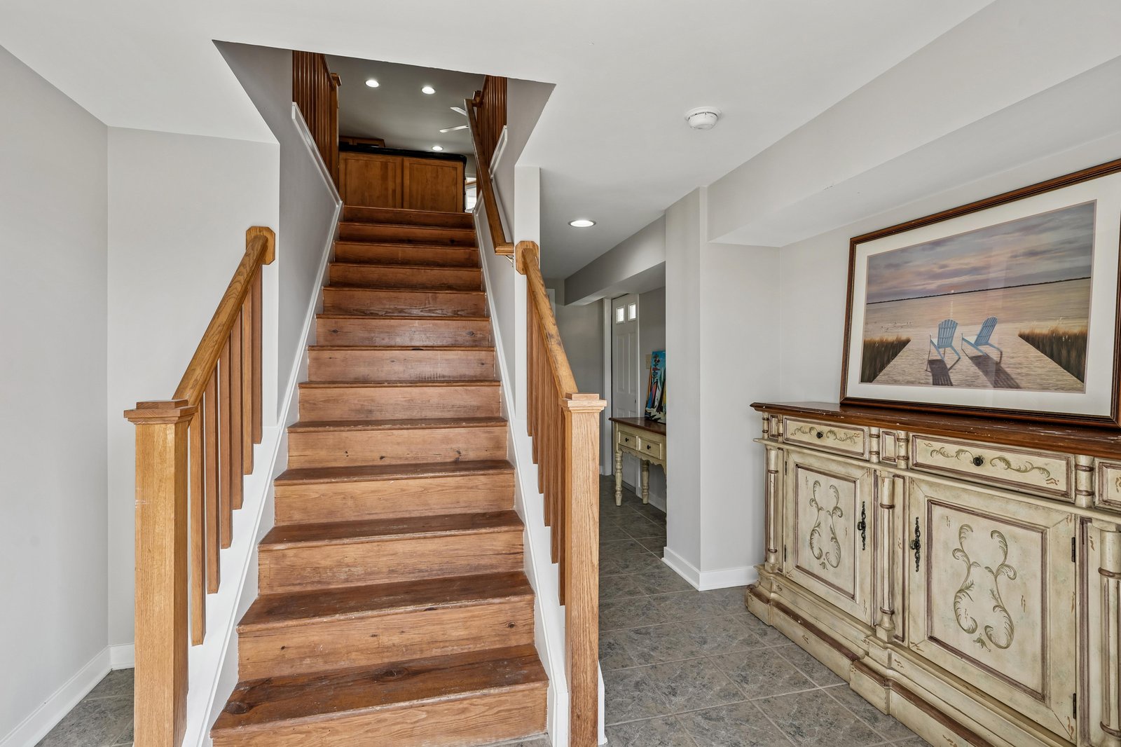 Bright open entryway welcomes you with warm hardwood stairs and coastal artwork hinting at the relaxing getaway ahead.
