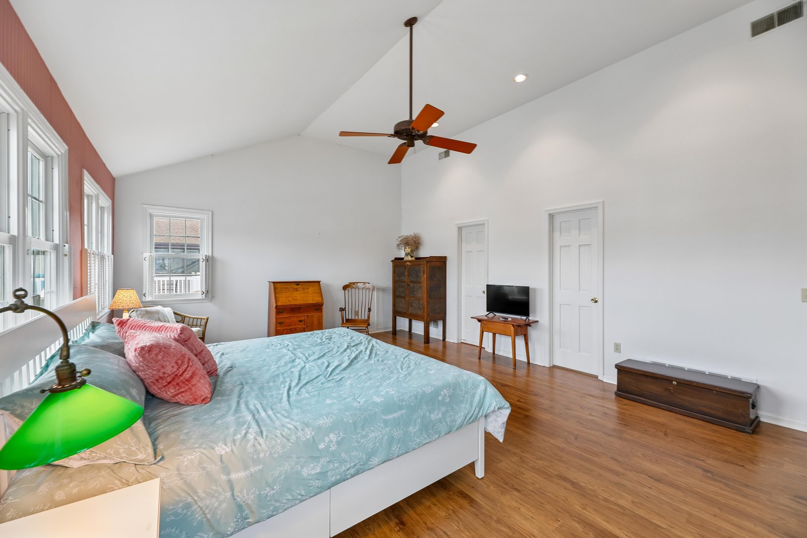 Unwind in your spacious, light-filled bedroom with vaulted ceilings and warm hardwood floors. The ceiling fan keeps you comfortable, while charming antique-style furnishings add character to your peaceful retreat.