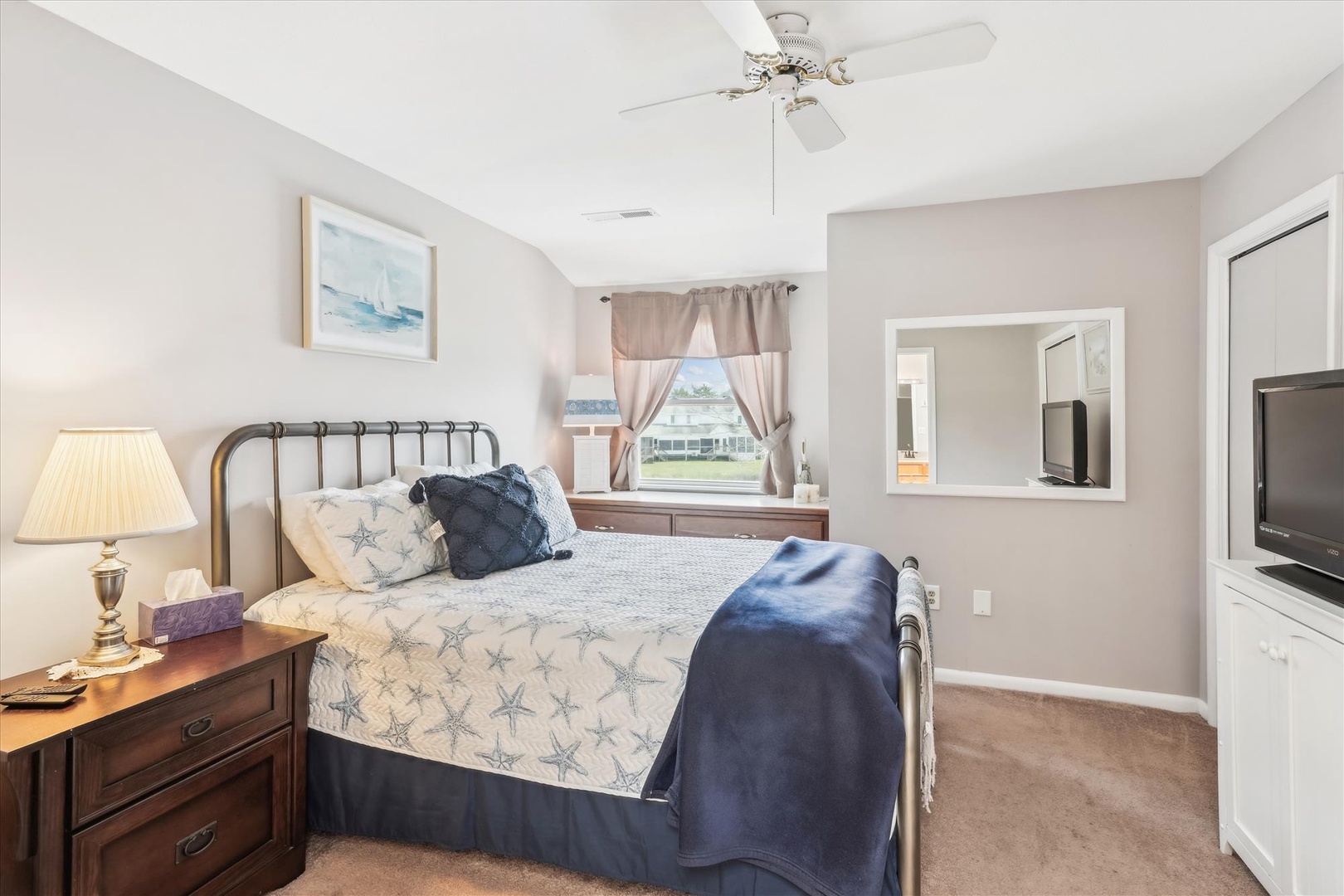 Sink into your plush bed with coastal-themed linens, enjoy the ceiling fan's gentle breeze, and wake up to natural light streaming through the window. The TV and ensuite bathroom are right at your fingertips.