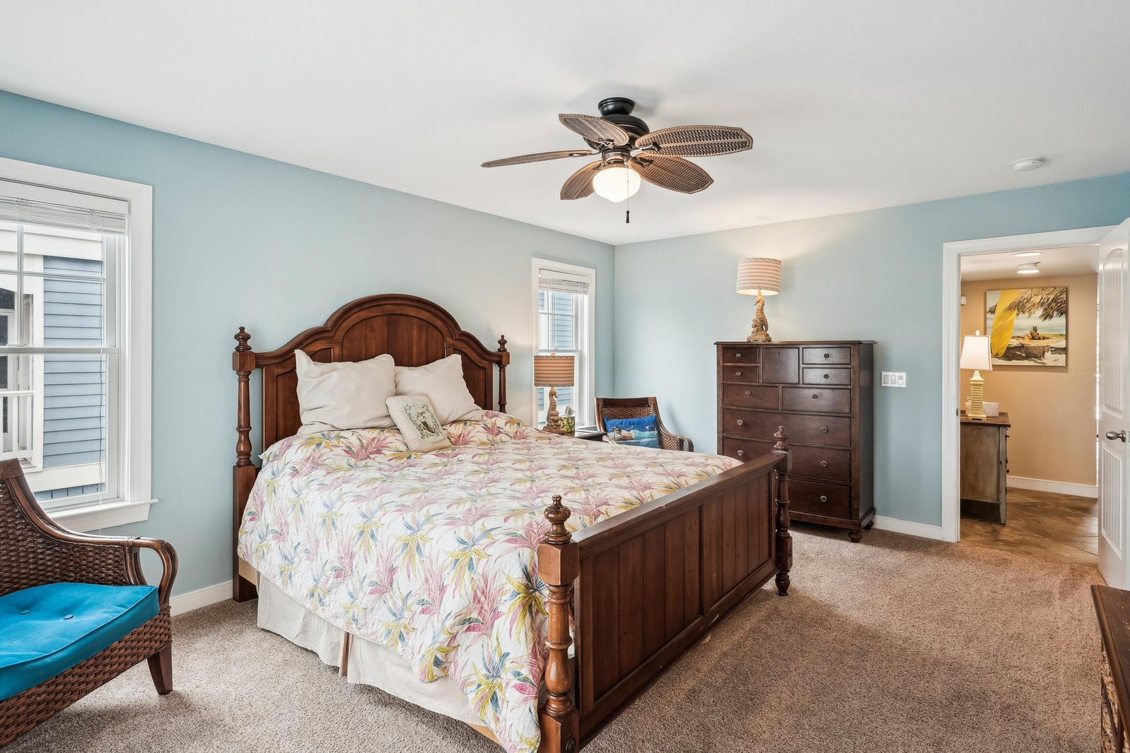 Your coastal-themed bedroom awaits with soft aqua walls, a plush tropical-print bed, and a gentle ceiling fan to keep you cool on warm summer nights.