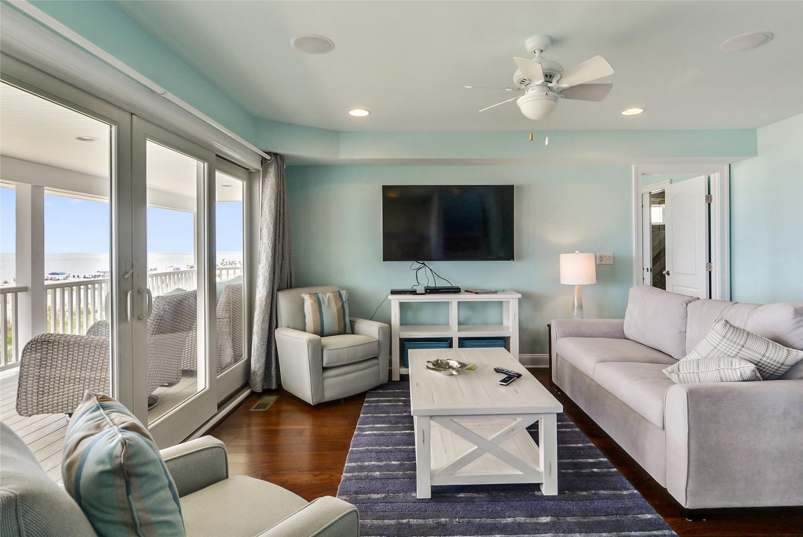 Relax in your bright coastal living space with soft seating, a large TV for movie nights, and glass doors opening to your balcony with water views.