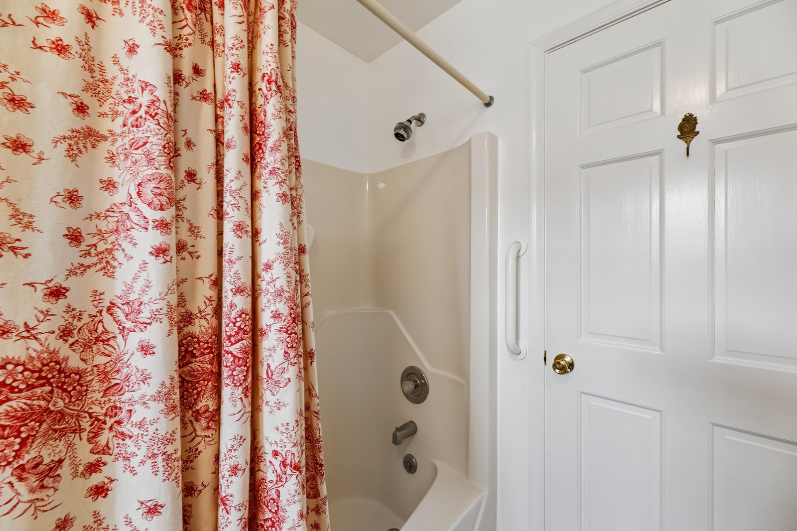 Your private bathroom features a shower-tub combo with fresh linens and charming toile curtains for a cozy, home-away-from-home feel.