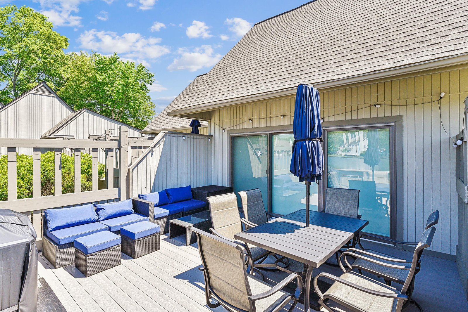 Step out onto your private deck where relaxation awaits—lounge on plush outdoor seating, dine al fresco under the blue umbrella, and enjoy easy access to the sparkling pool just beyond the glass doors.