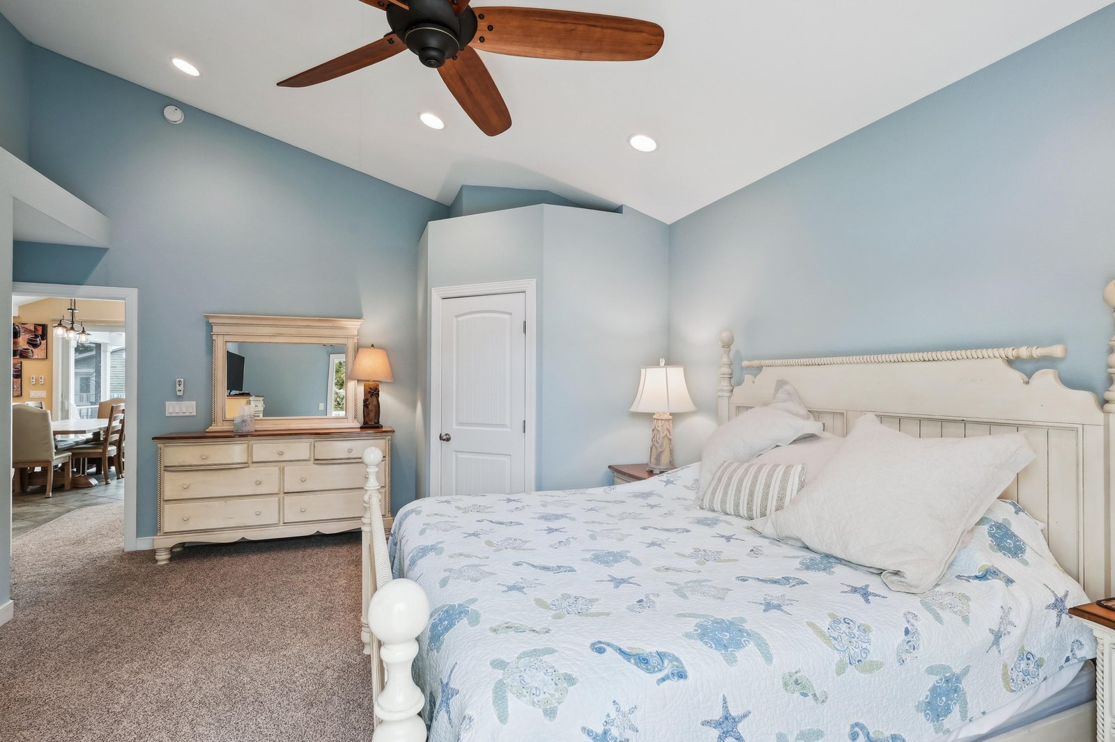 Your serene coastal bedroom awaits, with soothing ocean-inspired tones and a plush bed dressed in soft linens. Vaulted ceilings, warm lighting, and gentle ceiling fan breezes create the perfect retreat after a day of adventure.