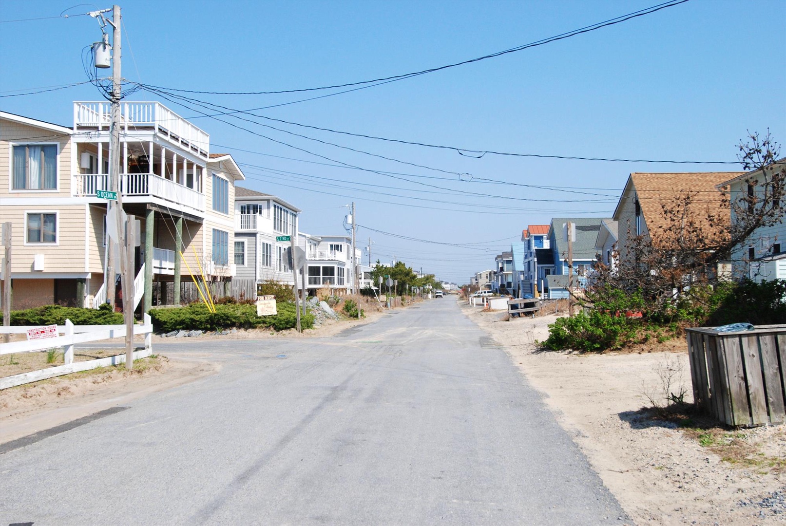 A quiet coastal street lined with beachfront vacation homes, offering easy access to sandy shores and ocean views.