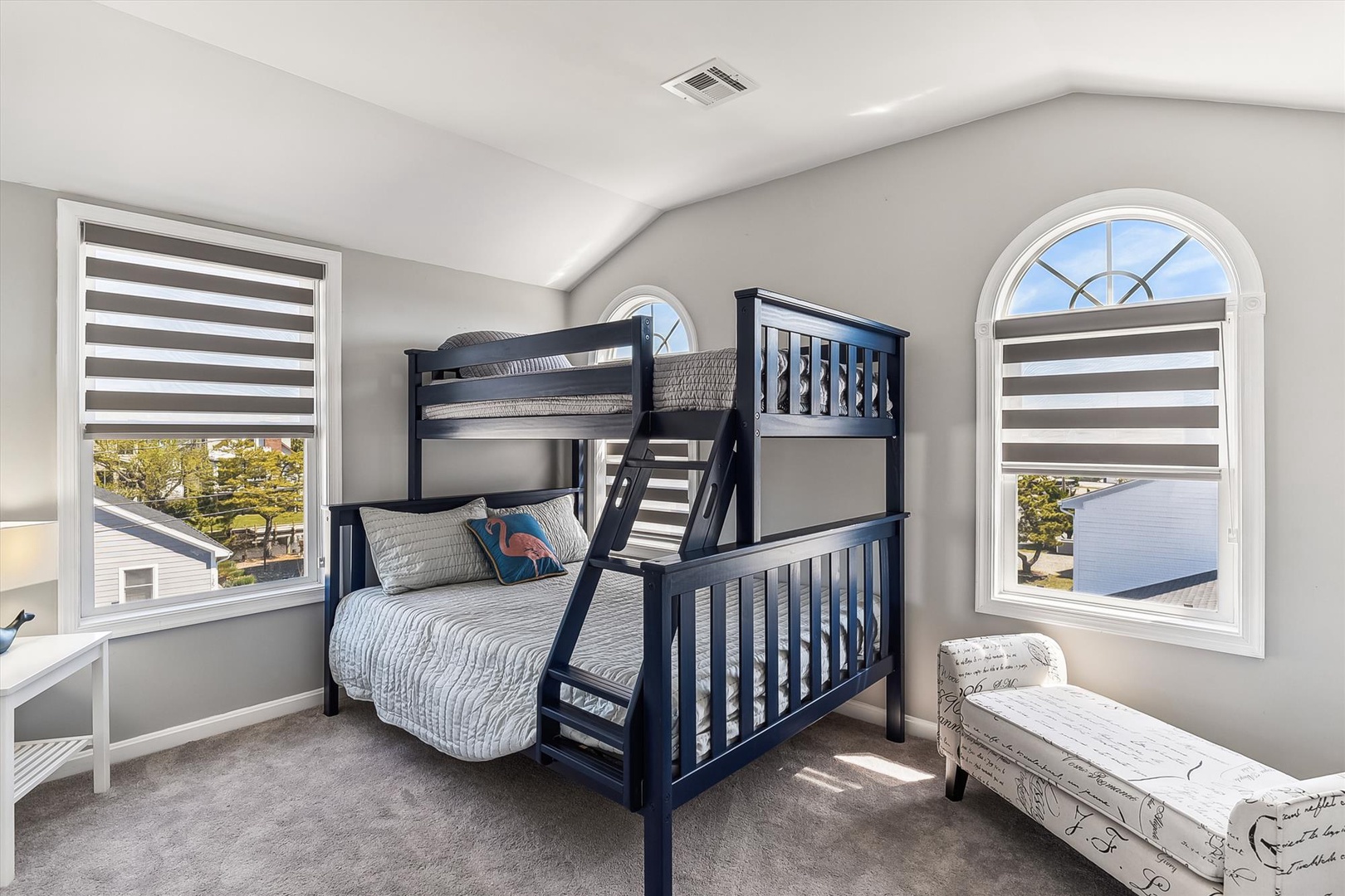 Perfect for families, this bright bedroom features a stylish bunk bed setup with coastal-inspired linens and two arched windows that flood your space with natural light.