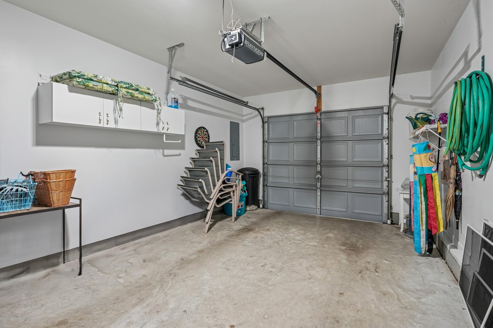 A clean, organized garage with ample storage space for beach gear, bicycles, and outdoor equipment. The automatic door opener and built-in cabinets provide convenient access and organization.